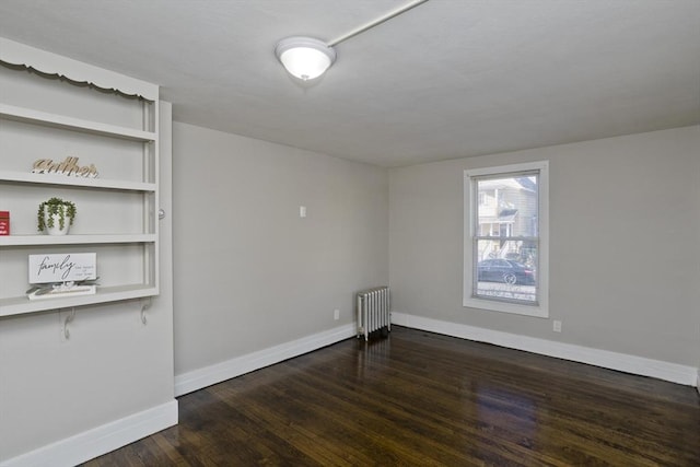 empty room featuring radiator and dark wood-type flooring