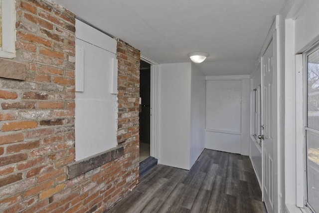 hallway with brick wall and dark hardwood / wood-style floors