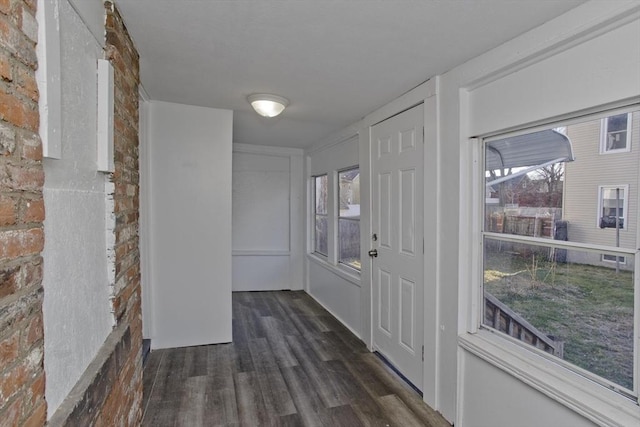 interior space with dark wood-type flooring and brick wall