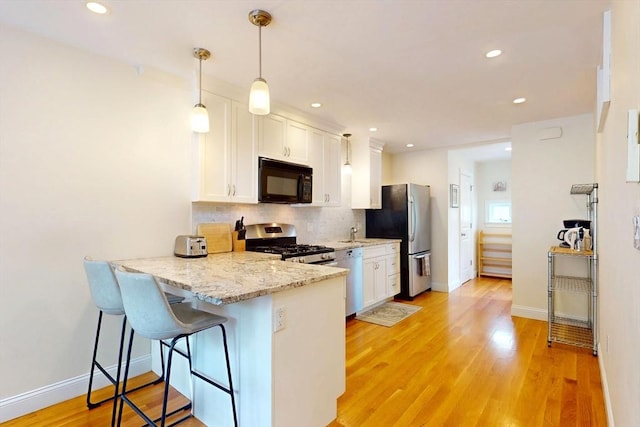 10 Bradbury St Unit 10, Boston, MA 02134 - kitchen featuring appliances with stainless steel finishes, white cabinets, tasteful backsplash, a peninsula, and recessed lighting