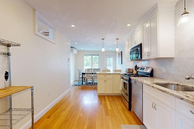 10 Bradbury St Unit 10, Boston, MA 02134 - kitchen with stainless steel appliances, a peninsula, light wood-style floors, a sink, and white cabinetry