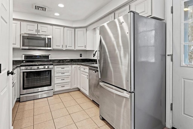 kitchen with appliances with stainless steel finishes, sink, light tile patterned floors, and white cabinets