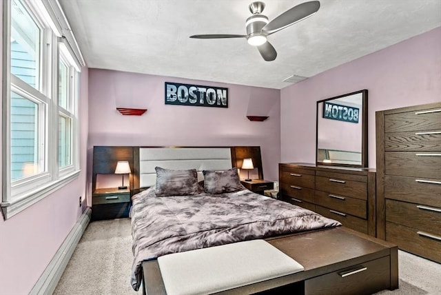 bedroom with a baseboard heating unit, light colored carpet, and ceiling fan