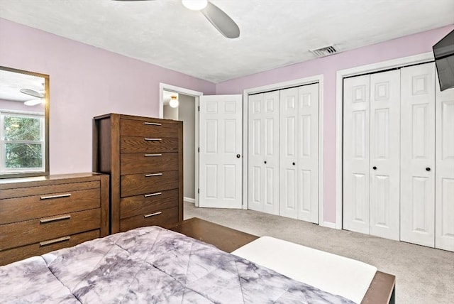 unfurnished bedroom featuring ceiling fan, light carpet, and two closets