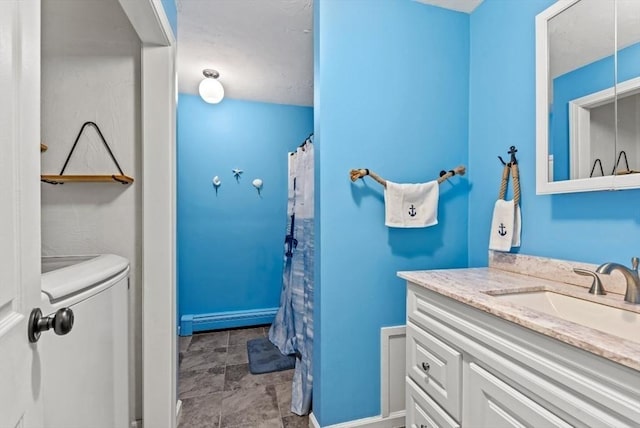 bathroom with baseboard heating, washing machine and clothes dryer, and vanity