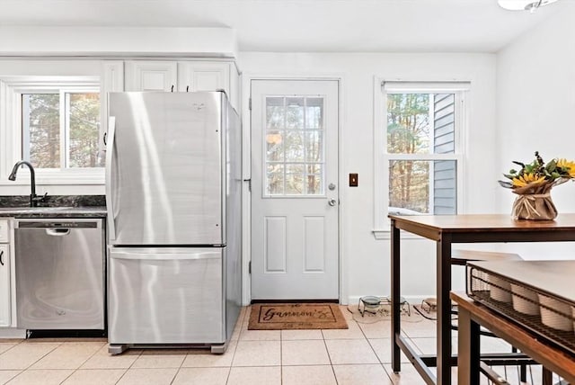 kitchen featuring stainless steel appliances, sink, light tile patterned floors, and white cabinets