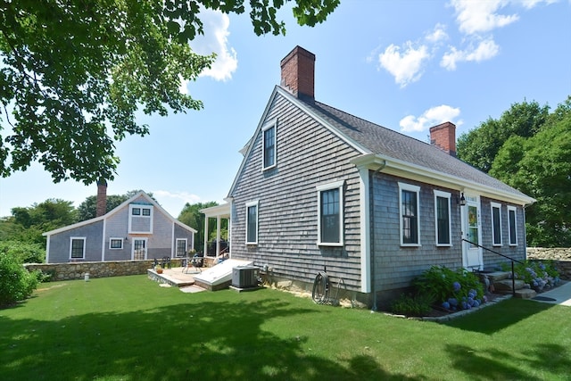 rear view of house featuring central AC and a lawn