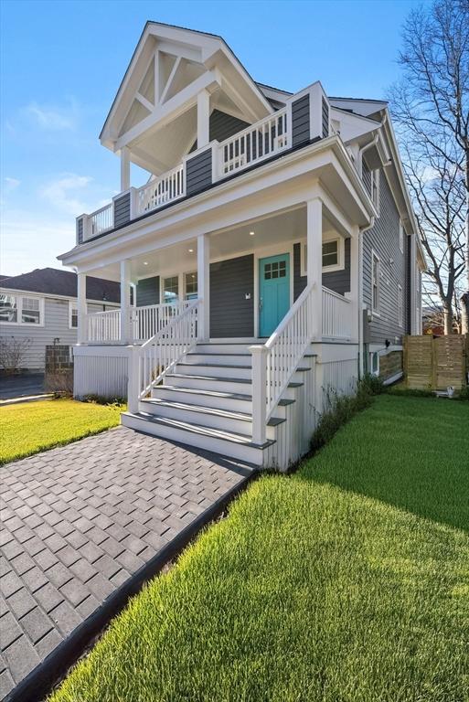 view of front of property featuring a front yard, a porch, and a balcony