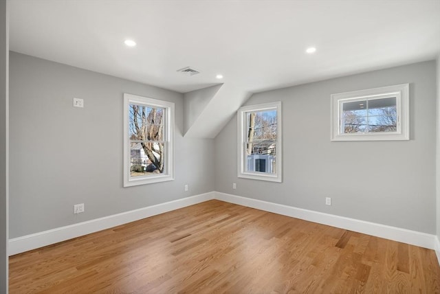 additional living space featuring light hardwood / wood-style flooring, a wealth of natural light, and lofted ceiling