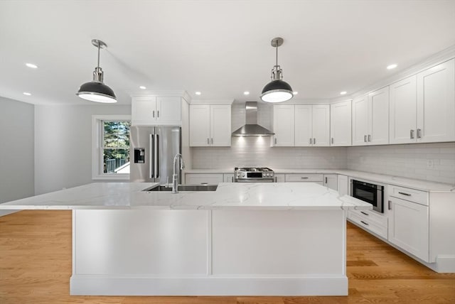 kitchen featuring sink, wall chimney range hood, white cabinetry, and appliances with stainless steel finishes