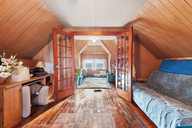 additional living space featuring vaulted ceiling, dark wood-type flooring, wooden walls, and french doors