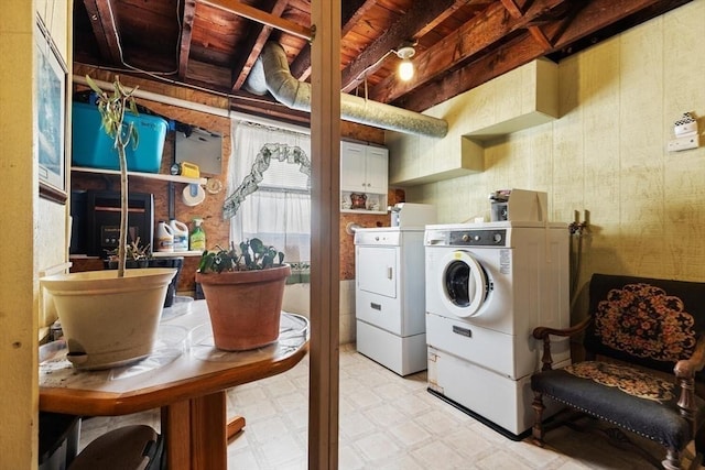 clothes washing area with washer and clothes dryer and cabinets