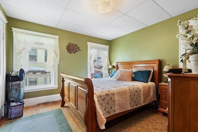 bedroom featuring a drop ceiling and light wood-type flooring