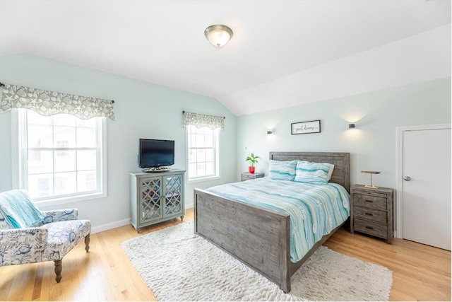 bedroom featuring baseboards, wood finished floors, and lofted ceiling