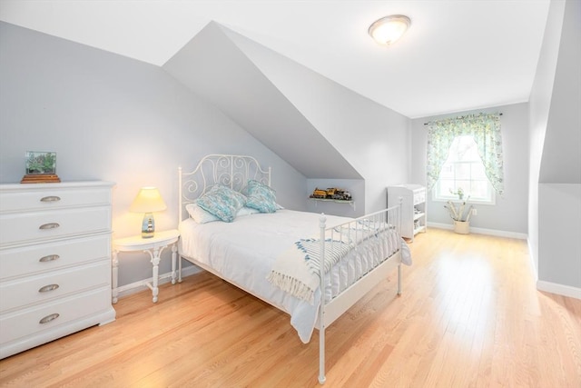 bedroom featuring light wood-type flooring, baseboards, and lofted ceiling