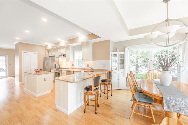 kitchen with crown molding, a kitchen island, stainless steel appliances, and plenty of natural light
