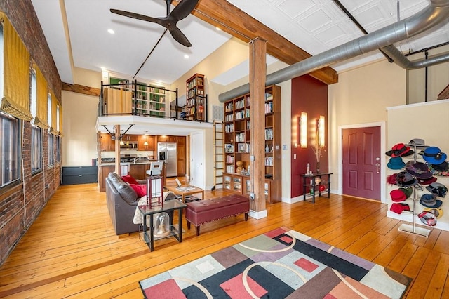 living room with light wood-style floors, ceiling fan, and a high ceiling