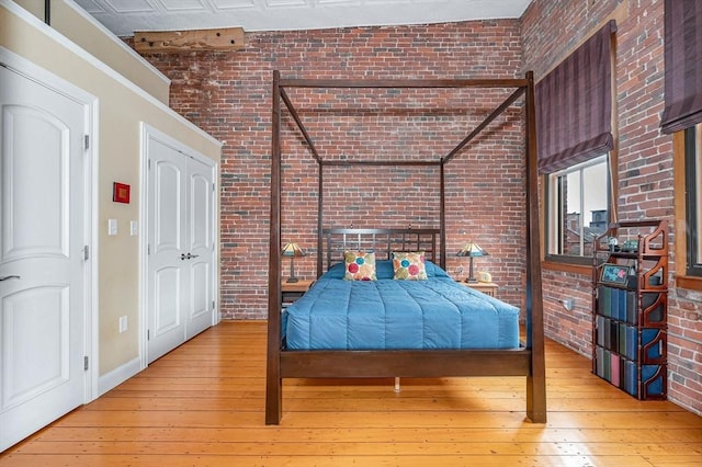 bedroom with hardwood / wood-style floors, baseboards, and brick wall