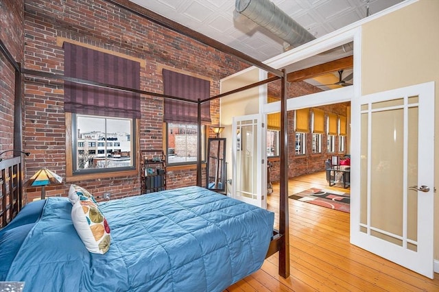 bedroom featuring an ornate ceiling, hardwood / wood-style flooring, brick wall, and a towering ceiling