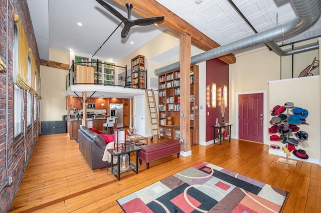 living area with wood-type flooring, ceiling fan, and a high ceiling