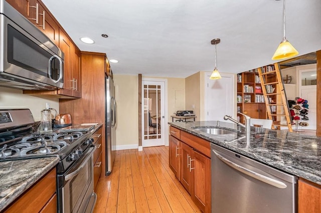 kitchen with brown cabinets, decorative light fixtures, appliances with stainless steel finishes, and a sink