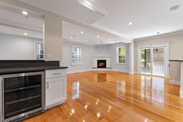 20 Winfield St Unit 1, Boston, MA 02127 - unfurnished living room featuring beverage cooler, ornamental molding, light wood finished floors, a warm lit fireplace, and recessed lighting