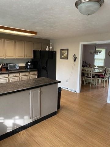 19 Camelot Ct Unit 19, Stoughton, MA 02072 - kitchen featuring black fridge with ice dispenser, dark countertops, light wood finished floors, baseboards, and a textured ceiling