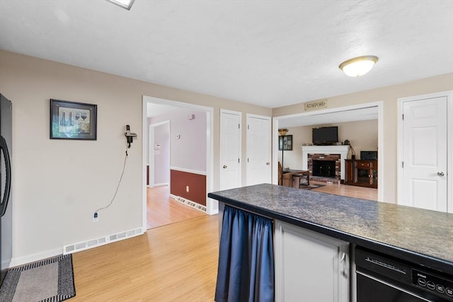 19 Camelot Ct Unit 19, Stoughton, MA 02072 - kitchen with dark countertops, light wood-style flooring, a brick fireplace, and baseboards