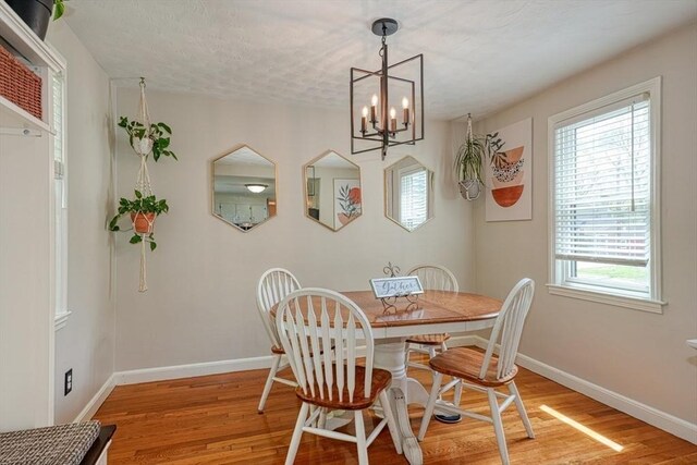 dining area with light wood-style floors, baseboards, and a chandelier