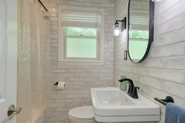 bathroom featuring toilet, a sink, and curtained shower