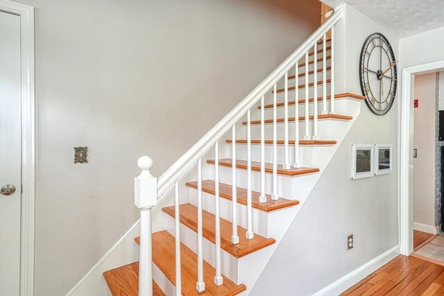 stairway featuring wood finished floors and baseboards