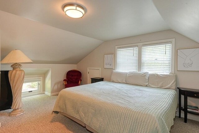 carpeted bedroom with vaulted ceiling and baseboards