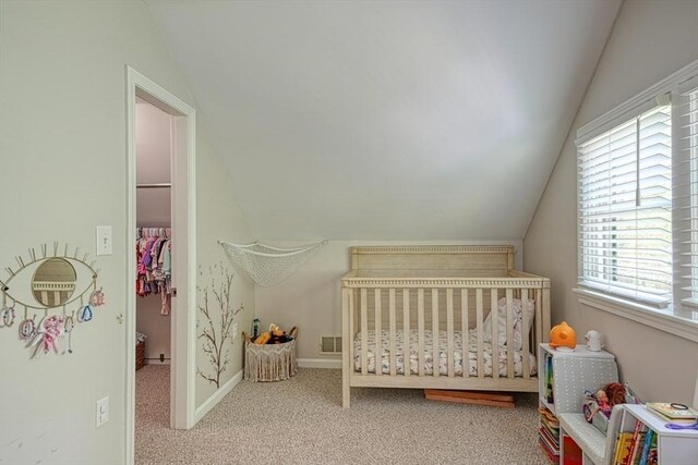 carpeted bedroom featuring lofted ceiling, a crib, multiple windows, and baseboards
