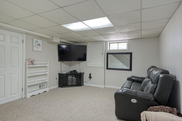 carpeted living room with a drop ceiling and baseboards