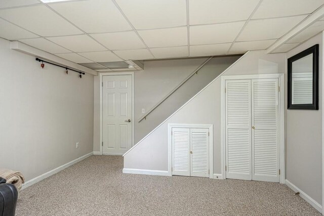 finished below grade area featuring carpet, a paneled ceiling, and baseboards