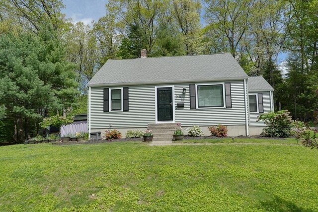 view of front of home featuring a front lawn, a chimney, and a shingled roof