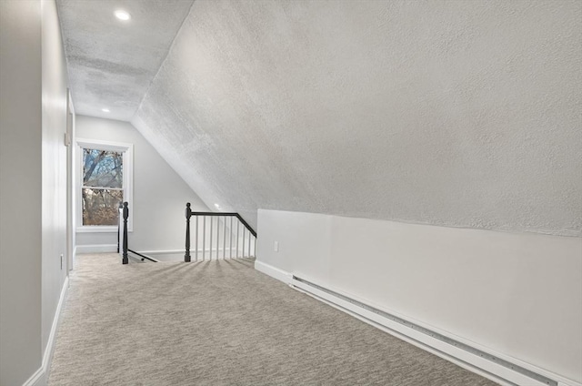 additional living space with a textured ceiling, lofted ceiling, carpet floors, and a baseboard heating unit