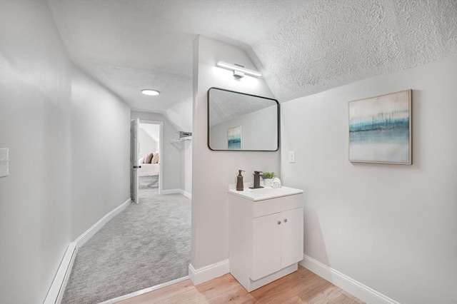 bathroom featuring lofted ceiling, a textured ceiling, hardwood / wood-style floors, and vanity