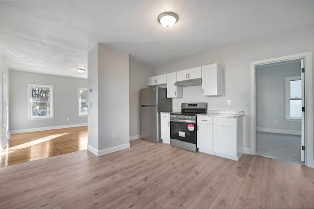 kitchen featuring appliances with stainless steel finishes, white cabinetry, light stone counters, and light hardwood / wood-style floors