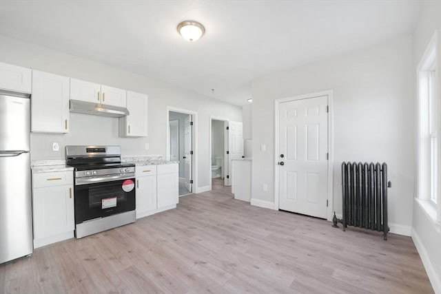 kitchen with stainless steel appliances, white cabinets, radiator heating unit, and light hardwood / wood-style flooring