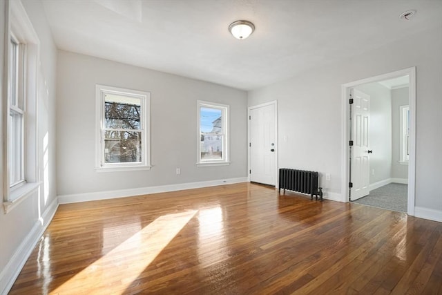 empty room with wood-type flooring and radiator