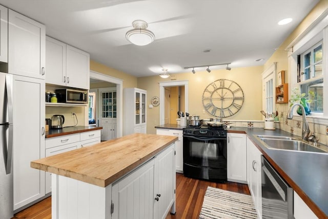 kitchen with appliances with stainless steel finishes, butcher block counters, a sink, and white cabinets
