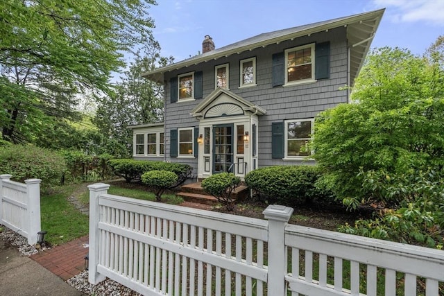 colonial-style house with a chimney and a fenced front yard