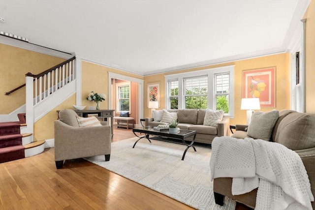 living room featuring light wood-style flooring, stairs, crown molding, and baseboards