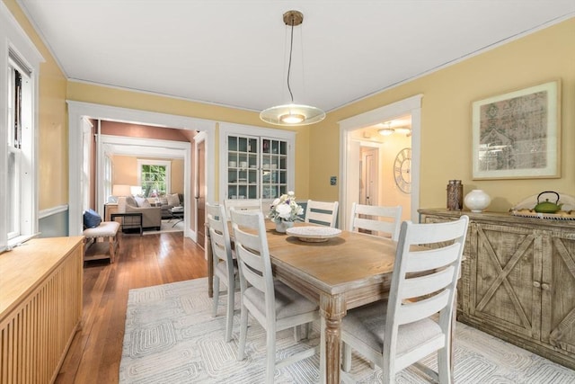 dining area featuring light wood-type flooring and crown molding