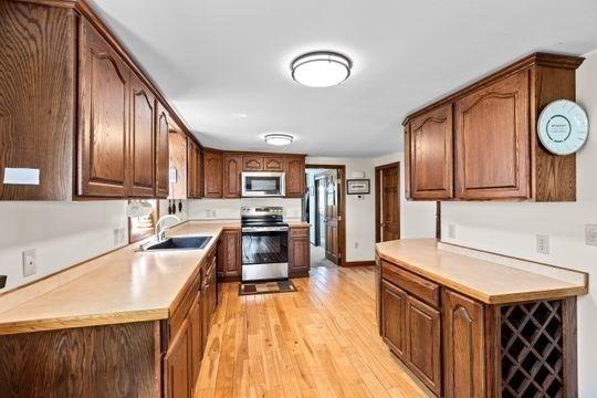 45 Rocky Nook Ave, Kingston, MA 02364 - kitchen with stainless steel appliances, a sink, light wood-type flooring, and light countertops