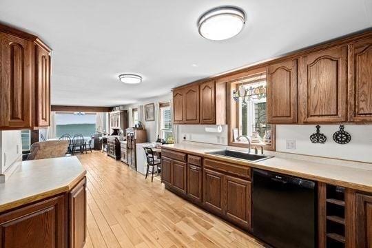 45 Rocky Nook Ave, Kingston, MA 02364 - kitchen featuring black dishwasher, a sink, light wood-style flooring, light countertops, and brown cabinets