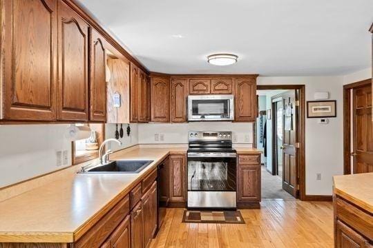 45 Rocky Nook Ave, Kingston, MA 02364 - kitchen featuring stainless steel appliances, a sink, light countertops, light wood-type flooring, and brown cabinets