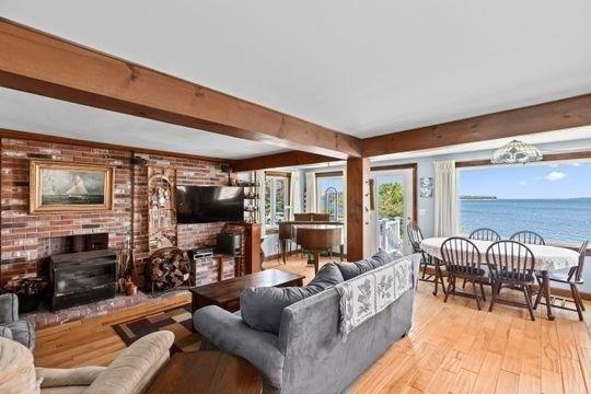 45 Rocky Nook Ave, Kingston, MA 02364 - living room featuring a fireplace, light wood-type flooring, beamed ceiling, and brick wall