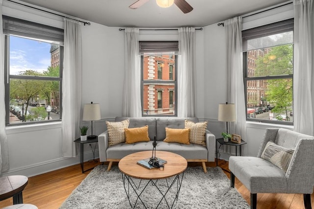 sitting room with healthy amount of natural light, light wood-type flooring, a ceiling fan, and baseboards